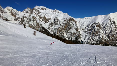 some-skier-driving-down-a-apline-ski-run-with-a-beautiful-mountain-scenery-in-the-background