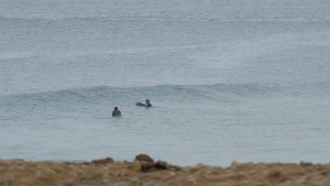 Two-young-bodyboarders-waiting-for-waves,-Carcavelos-beach-Portugal