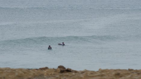 Dos-Jóvenes-Practicantes-De-Bodyboard-Esperando-Olas,-Playa-De-Carcavelos-Portugal