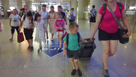 Chengdu,-China---July-2019-:-Western-family-surrounded-by-friendly-Chinese-crowd-leaving-high-speed-train-station-in-Chengdu