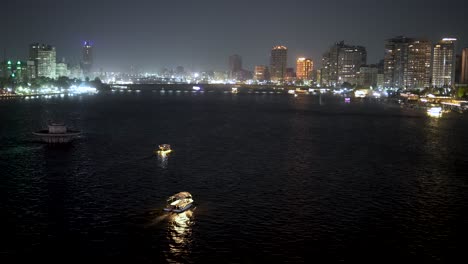 Crucero-Por-El-Río-Nilo-Y-Barcos-De-Fiesta-Con-El-Horizonte-De-La-Ciudad-De-El-Cairo,-Egipto,-Al-Fondo