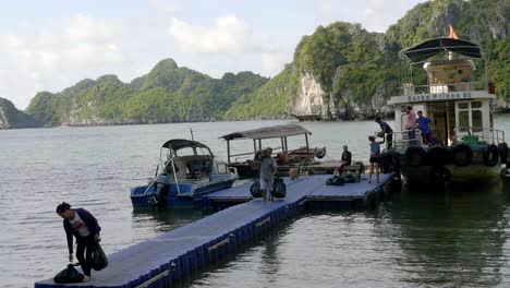 Bahía-De-Ha-Long,-Vietnam---Los-Turistas-Se-Embarcan-Desde-El-Velero-Hacia-Otro-Punto-De-Destino-Utilizando-El-Sendero-Flotante---Plano-General