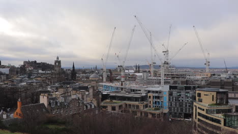 Multiple-cranes-in-operation-at-the-Edinburgh-St-James,-a-new-retail,-leisure,-hotel-and-residential-development-in-Edinburgh-City-centre,-with-a-view-of-the-construction-site-and-Edinburgh-skyline