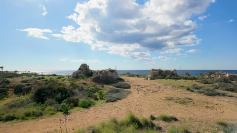 A-wide-view-of-the-coastal-landscape-at-the-Tombs-of-the-Kings-in-Pafos,-Cyprus,-with-scattered-rocks-and-greenery