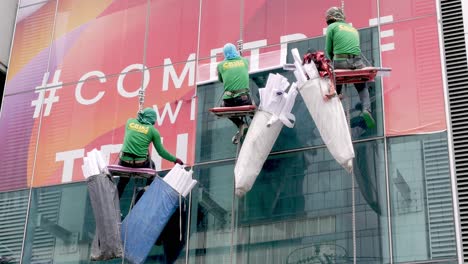 Das-Team-Klebt-Werbeaufkleber-Auf-Das-Glas-Eines-Hochhauses-Außerhalb-Von-Bangkok,-Thailand