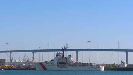 Alerta-De-Guardacostas-De-EE.-UU.-Wmec-630,-Barco-Cortador-De-Resistencia-Media-En-El-Puerto-Con-El-Puente-Coronado-Al-Fondo,-Vista-Panorámica-Hacia-Abajo-Para-Revelar-La-Toma-De-Establecimiento