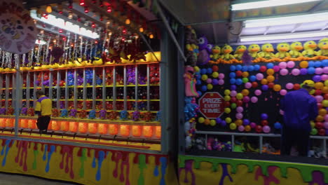 Fall-Fair-Medium-wide-shot-follows-a-row-of-carnival-game-stations