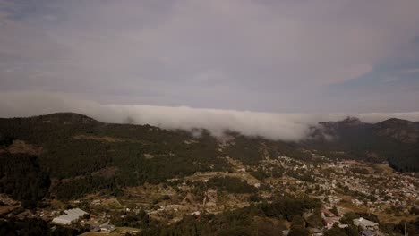 Aerial-drone-shot-of-mountain-range-of-pachuca-mexico-with-green-and-yellow-fields,-bank-of-clouds-200%-speed