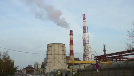 The-Chimney-Of-A-Factory-In-The-Industrial-District-Of-Legnica,-Southwest-Poland-With-Smoke-Rising-To-The-Sky---Tilt-Up-Wide-Shot