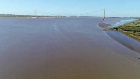 Una-Vista-Aérea-Inversa-Del-Río-Humber-En-El-Reino-Unido-Que-Muestra-Las-Marismas-Y-El-Icónico-Puente-Humber-Al-Fondo.