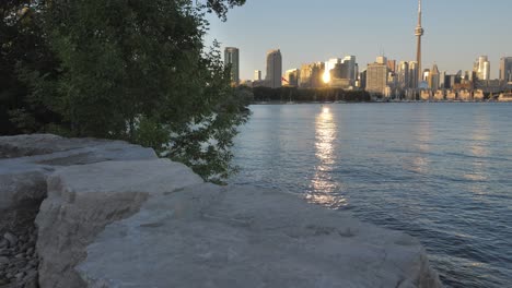 Tilt-up-from-hiking-trail-to-reveal-Toronto-skyline-and-waterfront-at-sunset