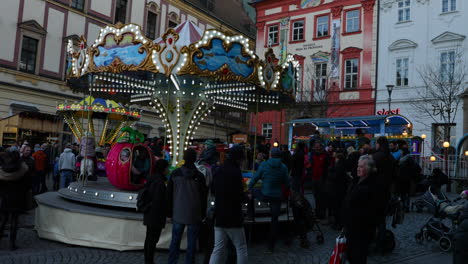 Strömende-Menschenmassen-Während-Des-Weihnachtsmarkts-In-Der-Nähe-Der-Karussellkette-Für-Kinderattraktionen-Auf-Den-Märkten-Am-Zeleny-Platz,-Aufgenommen-In-4K-60fps-Zeitlupe