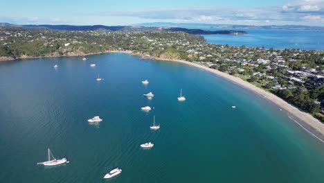Veleros-Y-Yates-Flotando-En-El-Tranquilo-Mar-Azul-Junto-A-La-Gran-Playa-De-Oneroa-En-La-Isla-Waiheke,-Auckland,-Nueva-Zelanda