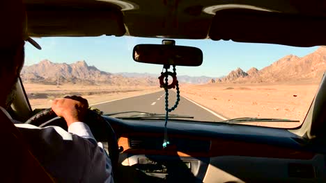 Passenger-seat's-point-of-view-from-an-old-taxi-driving-on-a-long-straight-road-in-the-sunny-arabian-desert