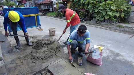 Foremen-wearing-safety-reflective-vests-used-their-shovel,-mixed-cement,-and-demolition-hammer-to-perform-excavation-beside-the-road-gutter-to-install-new-water-piping-from-the-main-water-line