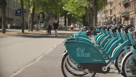 Renting-bikes-in-central-Gothenburg-while-people-walking-by-on-a-sunny-summer-day