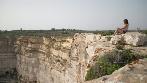 Magnificent-view-of-young-woman-near-the-Ta-Cenc-cliffs-on-the-rocky-coast-in-Sannat-on-the-island-of-Gozo,-Malta