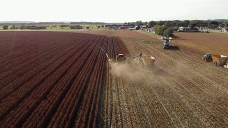 aerial-view-rotating-countr-clockwise-from-behind-a-harvester-picking-seed-corn-for-next-years-planting-as-dust-drifts-to-the-right