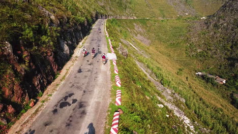 Low-drone-view-of-motorcyclists-taking-off-after-resting-on-the-road-on-the-Northern-Loop,-Ma-Pi-Leng-Pass