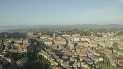 Toma-De-Drone-De-Siena,-Italia,-Comenzando-Con-La-Ciudad-Con-La-Noria-Al-Fondo,-Panorámica-Hacia-La-Izquierda-Revelando-El-Centro-Antiguo-Y-La-Piazza-Del-Campo,-Torres-E-Iglesias-Circundantes.