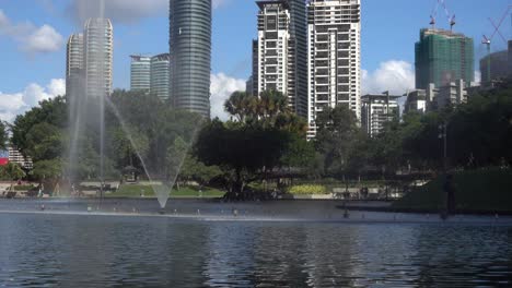 Atracción-De-Espectáculo-De-Fuente-En-El-Parque-Público-Con-Un-Edificio-Emblemático-Y-Un-Cielo-Azul-En-El-Fondo