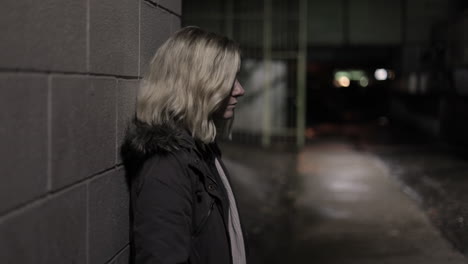 Girl-leans-against-a-wall-in-an-alley-at-night