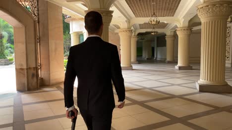 Un-Hombre-Guapo-Con-Traje-Parece-James-Bond-Y-Se-Aleja-Con-Un-Arma-En-La-Mano-Dentro-De-Un-Edificio-Con-Pilares.