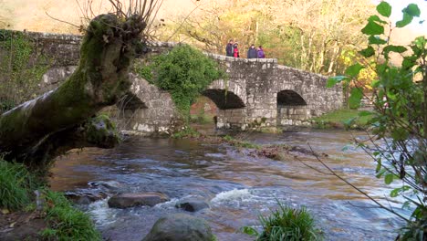 DARTMOOR,-DEVON,-UNITED-KINGDOM,-NOVEMBER-15,-2020,-Some-people-crossing-the-fingle-bridge-over-the-teign-river-in-Dartmoor-national-park