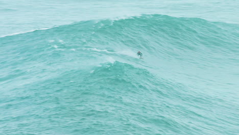 Surfer-races-across-turquoise-wave-in-turquoise-ocean-off-Nazare-coast