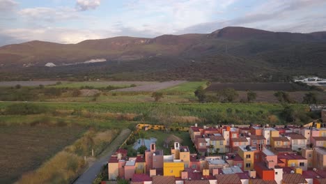 Aerial-drone-shot-in-Mexico-morelos-with-green-fields-and-some-houses-in-sunset