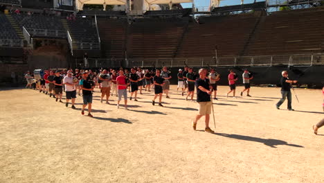 Drone-shot-circling-around-pipes-and-drums-musicians-marching-and-leaving-the-roman-arena-in-Avenches-Switzerland