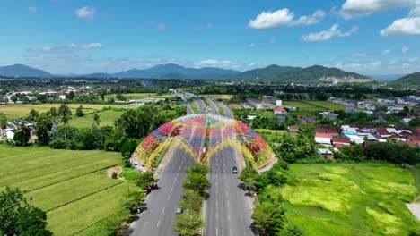 Drones-Sobrevuelan-La-Puerta-De-Entrada-De-Tembolak-En-La-Carretera-Con-Cielo-Azul-Y-Cordillera