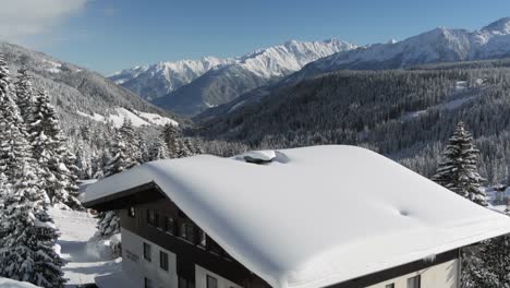 Scenic-view-of-a-snow-covered-chalet-in-sunny-weather-with-mountains-in-background