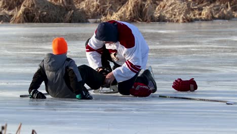 Un-Padre-Ayudando-A-Su-Hijo-Menor-A-Ponerse-Los-Patines-De-Hockey