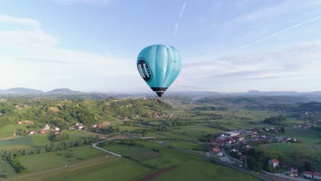 Aerial-forward-push-then-pan-to-reveal-second-balloon-and-sun-rising-over-beautiful-landscape