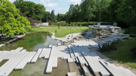 Grüner-Park-Mit-Wasserfall-An-Einem-Schönen-Sommertag,-Umgeben-Von-üppigem-Grün-Und-Gras