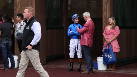 Footage-of-a-jockey-and-horse-trainer-having-an-in-depth-discussion-in-the-paddock-at-Churchill-Downs-before-a-big-horse-race,-highlighting-their-strategic-planning