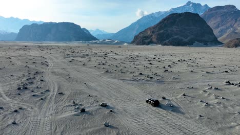 Vista-Aérea-Del-Frío-Desierto-De-Sarfaranga-Shigar-Con-Suv-Conduciendo-Por-El-Camino