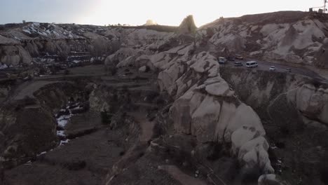 Uchisar-Castle,-Cappadocia,-Mountain-Cave-in-the-Distant-Desert---Rise-Up-Lens-Flare-Reveal,-The-Lonely-Mountain-stock-Footage,-desert-sunrise,-sunset,-Uçhisar,-Cappadocia