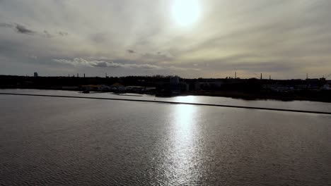 Letonia,-Europa---Un-Tramo-Sereno-Del-Río-Daugava-Bajo-Un-Cielo-Parcialmente-Nublado-Con-El-Reflejo-Del-Sol-Brillando-En-El-Agua---Drones-Volando-Hacia-Adelante