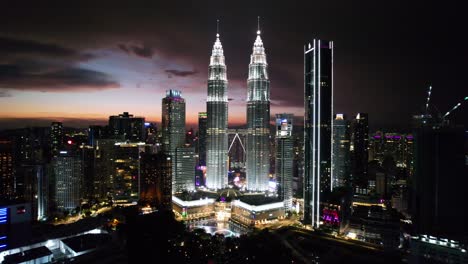 Luftdrohne,-Die-Bei-Sonnenuntergang-In-Richtung-Der-Berühmten-Skyline-Von-Kuala-Lumpur-Fliegt,-Während-Die-Gebäude-Den-Himmel-In-Malaysia-Erleuchten