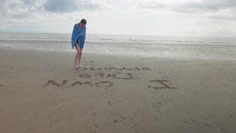 Young-girl-creative-writing,-sandy-beach,-bare-feet,-towel-dry,-slow-mo