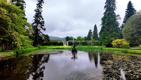 Ireland-Epic-locations-Powerscourt-Gardens-Wicklow-pond-with-ornate-fountain-and-enterance-to-the-walled-gardens-in-Summer