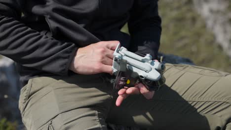 Close-Up-View-Of-Male-Taking-Out-Folded-Drone-From-Jacket-Pocket-And-Unfolding-Arms-Preparing-It-For-Flight