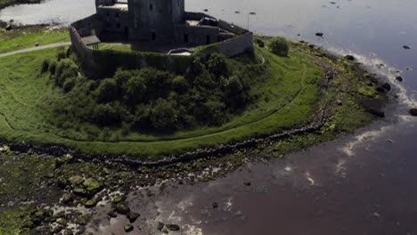 Dunguaire-Castle:-Aerial-tilt-up-from-sunlit-water-reflection-to-the-castle