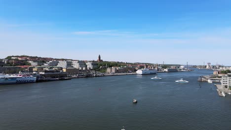 Forward-areial-drone-flight-towards-the-Gota-Alv-river-with-commuting-ferries-and-Gothenburg-city-scape-in-the-background-on-a-sunny-day-in-Sweden