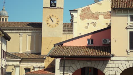 Iglesia-Y-Torre-Campanario-De-Un-Pequeño-Pueblo-De-Italia-Con-Bar-Y-Cafetería-Bajo-Los-Patios.