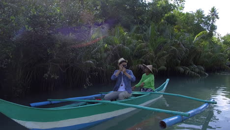 Touristenfotograf-Und-Fischer-Auf-Einem-Boot,-Das-Durch-Einen-Stillen-Fluss-Namens-Bojo-Philippinen-Reist