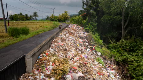 Hidden-burning-garbage,-spoiled-countryside-scenery,-passing-motorbike