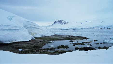 An-Land-In-Der-Antarktis-Mit-Gletscherlandschaft,-Küstenlandschaft-Der-Antarktis-Halbinsel-Mit-Schneebedecktem-Land-An-Der-Küste-Mit-Bergen-Und-Dem-Südlichen-Ozean